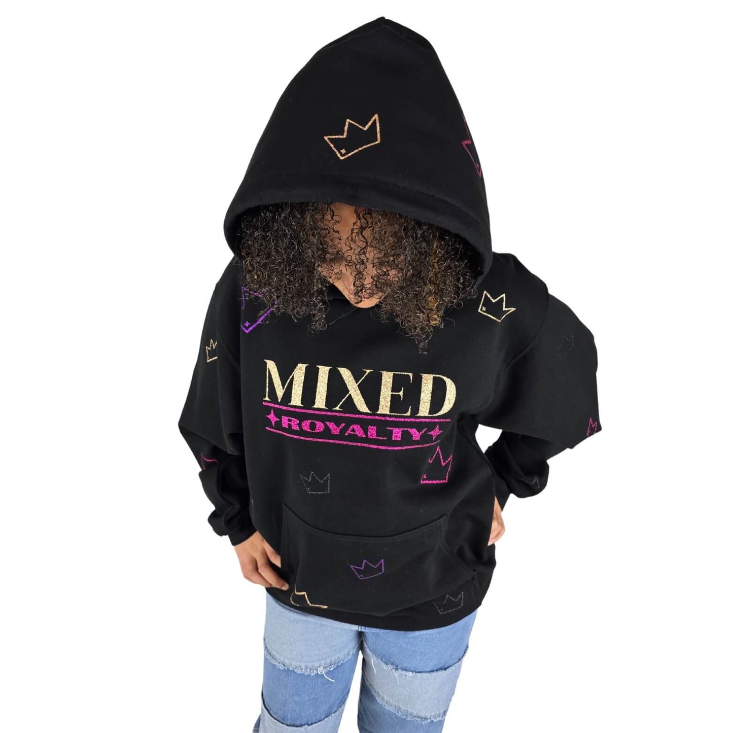 Biracial youth wearing a black 'Mixed Royalty' hoodie with the hood up, gold and purple sparkle lettering and sparkle crowns randomly all over. Empowering mixed-race kids clothing celebrating confidence and cultural pride.