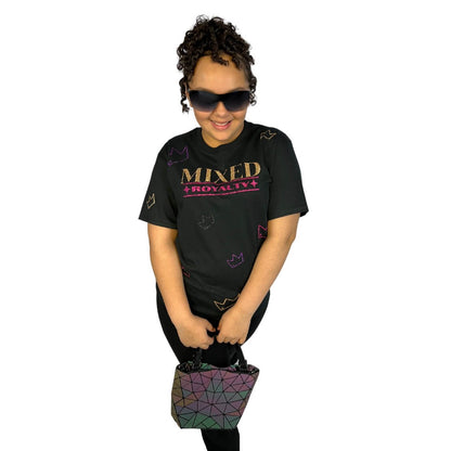 Child with curly hair wearing a black t-shirt with 'MIXED ROYALTY' text and crown sparkly pattern, holding a colorful geometric bag on a white background