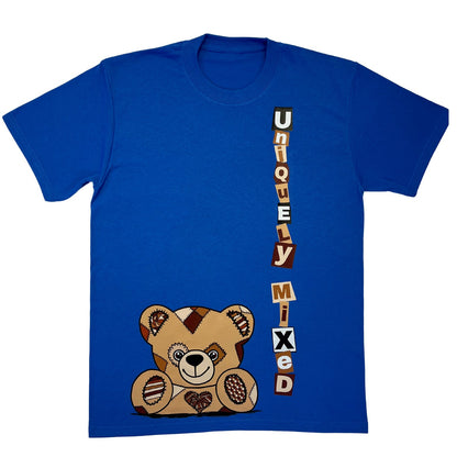Blue t-shirt flat lay with a teddy bear graphic peeking up from the bottom of the t-shirt and 'Uniquely Mixed' text vertically on a white background.