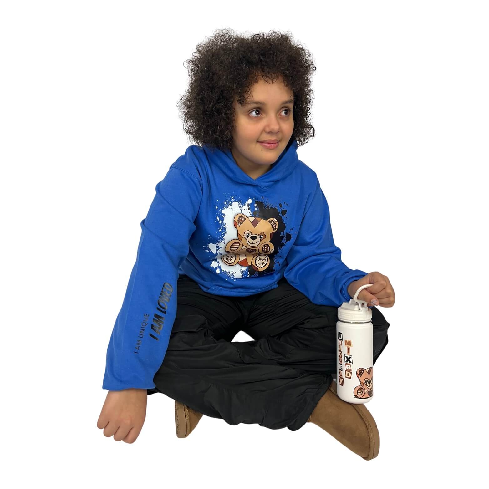Child wearing a Uniquely Mixed Unity Bear blue hoodie with a teddy bear design, sitting on the floor holding a white water bottle.
